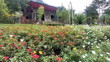 A building with a red roof and a garden with various flowers.