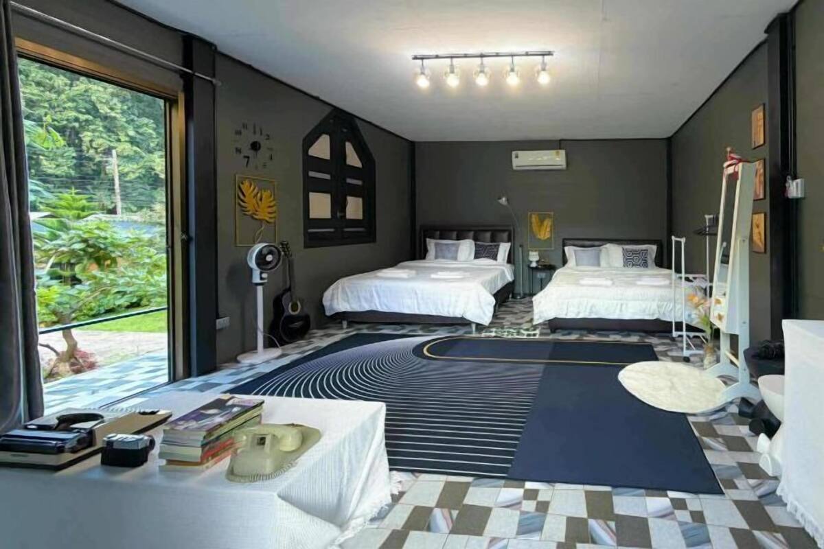 Una habitación con dos camas, un ventanal grande, un escritorio con libros y un suelo con un diseño original.