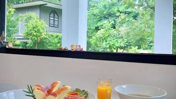 A breakfast table with a plate of food, a glass of orange juice, and a bowl.