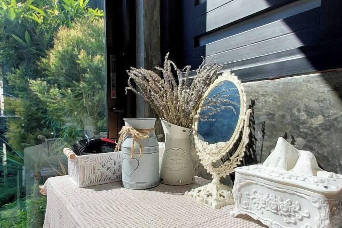Una mesa con un jarrón de flores secas, un espejo decorativo y una pequeña caja blanca con diseños intrincados.