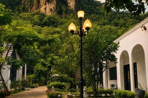 A pathway lined with a street lamp and a building with arched windows. - Vrapat (Chiang Dao)