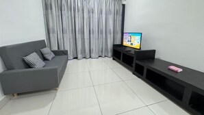 A modern living room with a grey sofa, a flat-screen TV, and a black entertainment unit.