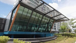 Een modern gebouw met een glazen gevel en een blauw betegelde plint.