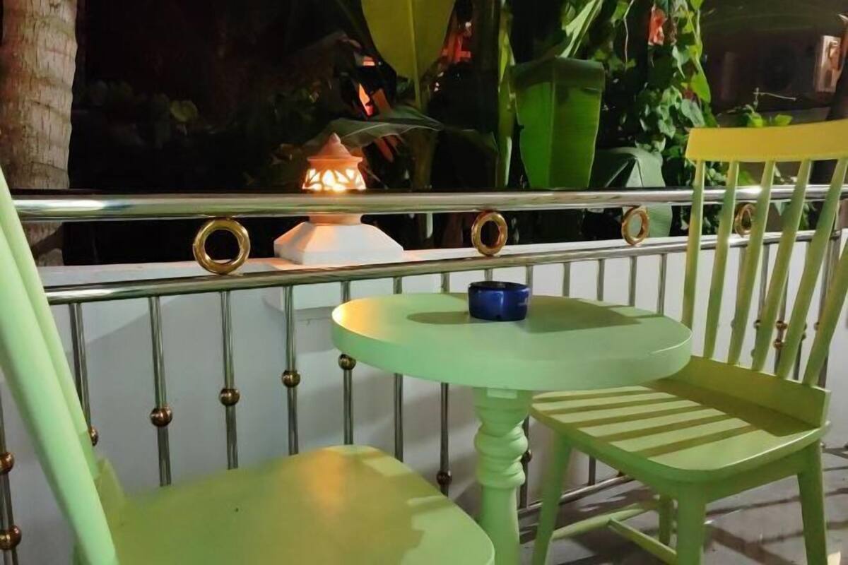 Un ensemble de chaise et de table verts, placé devant une rambarde métallique, avec une lanterne décorative.