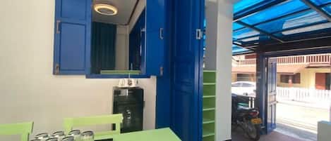 Ein Zimmer mit einem grünen Tisch, einem blauen Schrank und einem Motorrad vor dem Haus.