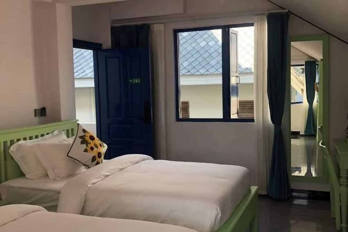 Une chambre d’hôtel avec un lit, une fenêtre avec des rideaux, une porte et une vue sur l’extérieur.