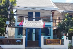 A two-story building with a gated entrance, a signboard, and a flag. - Vip Kingson Guest House (Luang Prabang)