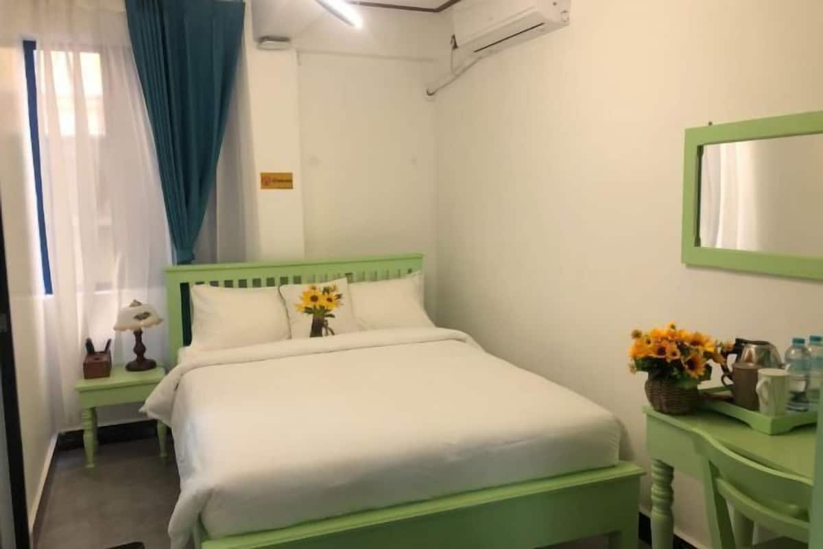 Une chambre avec un lit, une table de chevet, un miroir et une commode.