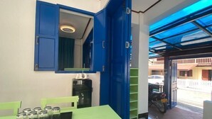 A room with a green table, a blue cabinet, and a motorcycle outside. - Vip Kingson Guest House (Luang Prabang)