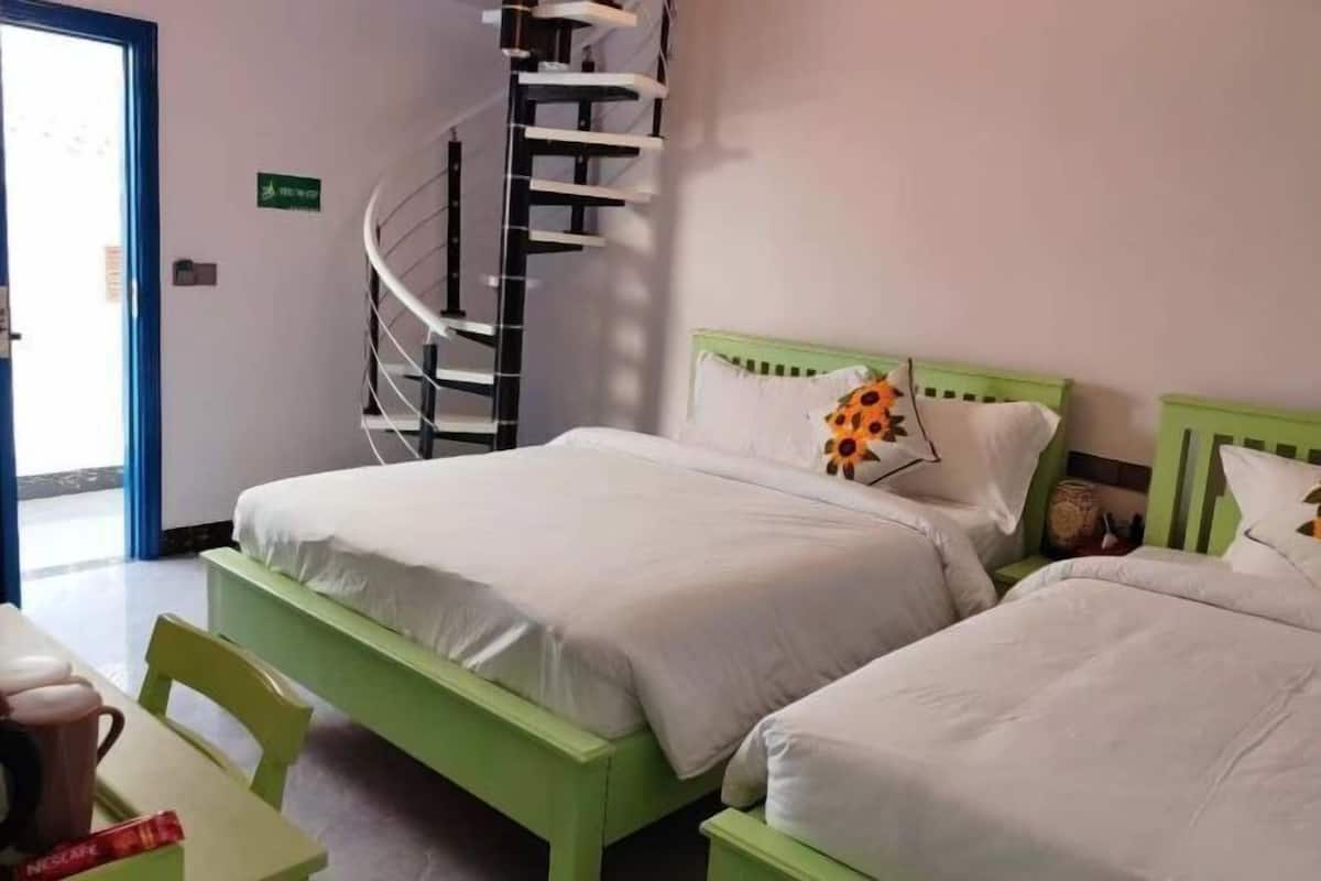 Une chambre d’hôtel avec un lit, une chaise, une petite table et un escalier en colimaçon.