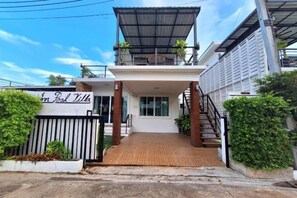 Un edificio de dos pisos con un porche, un letrero que dice 'Inn Pool Villa' y una escalera que lleva al nivel superior.