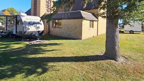 A small brick building with a chimney, a tree in front, and a covered RV parked nearby. - unique 3BR lodge w/ basic amenities & two RV's on 1.58 acres in beautiful Oldham (Oldham)