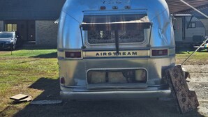 A vintage Airstream trailer parked in front of a building with a tower. - unique 3BR lodge w/ basic amenities & two RV's on 1.58 acres in beautiful Oldham (Oldham)