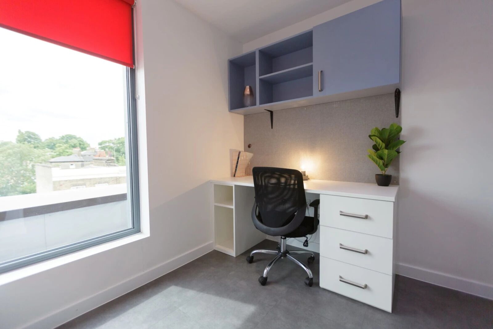 A modern office space with a desk, chair, and shelving unit.