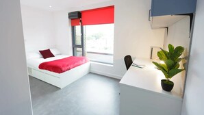 Ein modernes Schlafzimmer mit einem Bett, einem Schreibtisch und einem Fenster mit einem roten Rollo.
