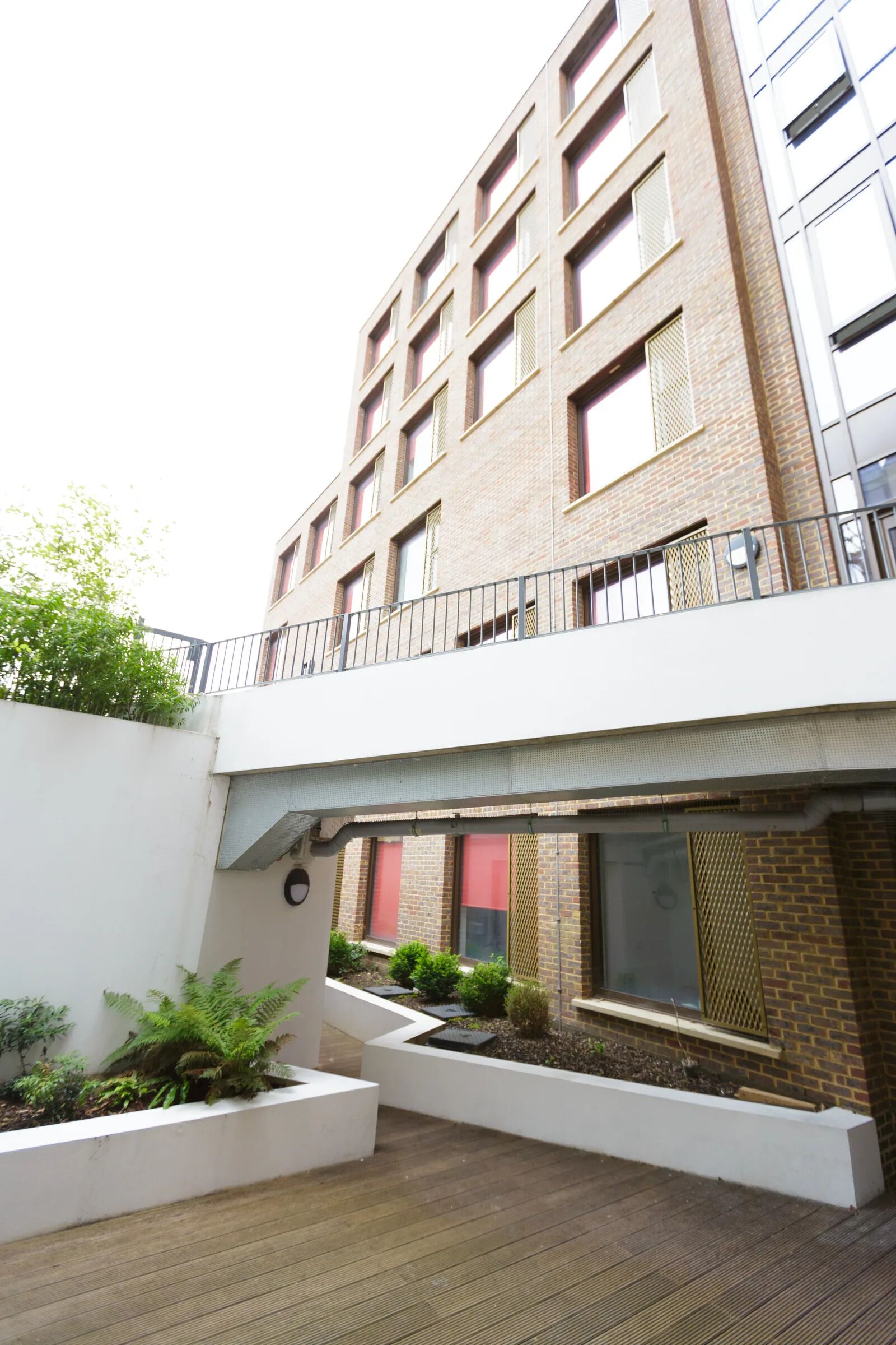 A multi-story building with a flat roof terrace, outdoor seating areas, and a white railing.