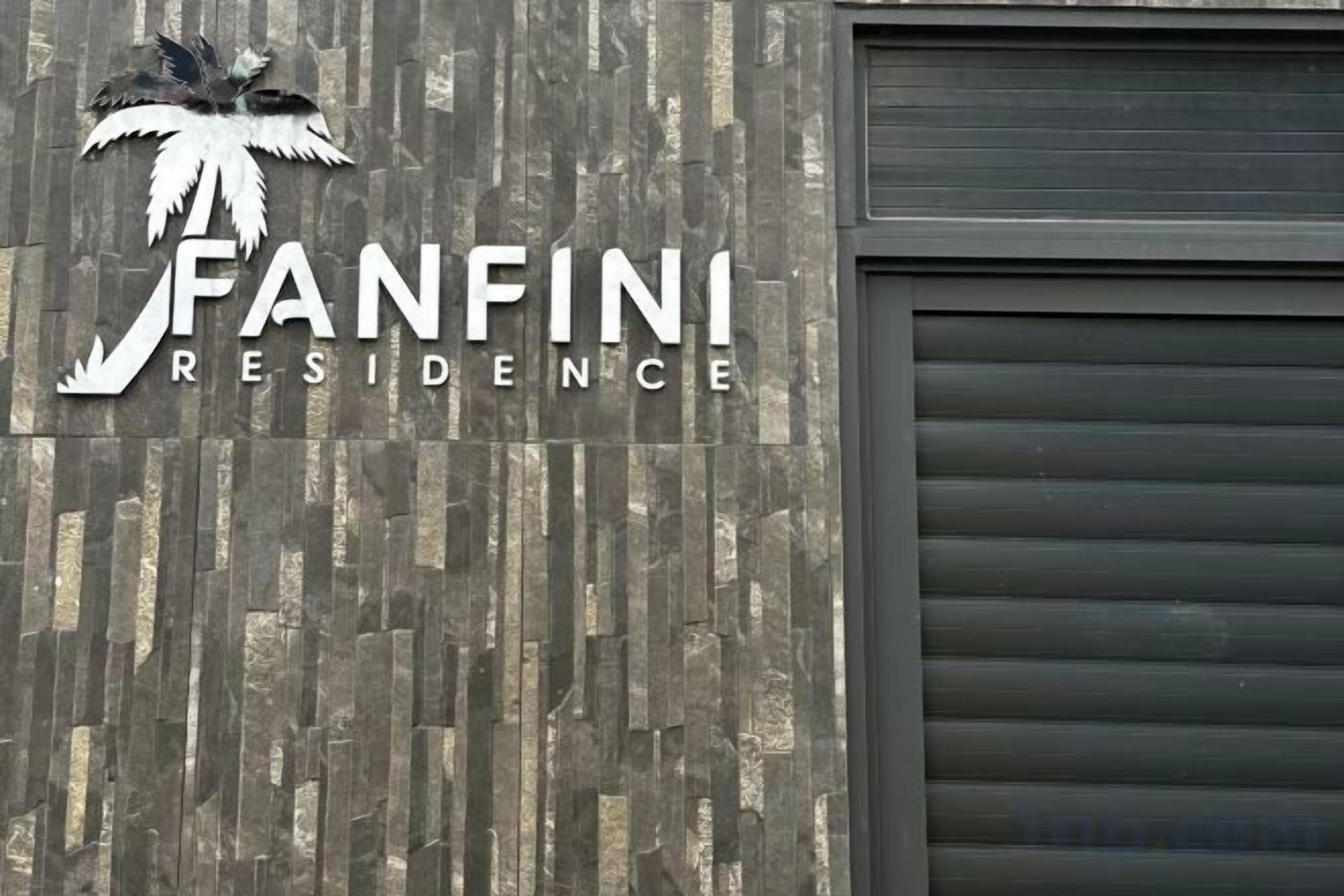 Ein Gebäude mit einem Schild, das 'FANFINI RESIDENCE' zeigt, und einem Palmenlogo.