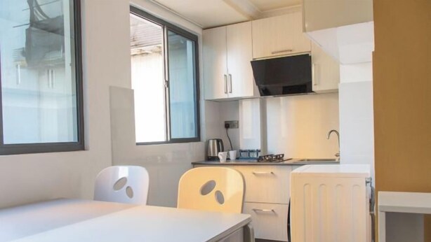 A compact kitchenette with white cabinets, a microwave, and a small dining area with a table and two chairs. - Fanfini Residence Male’ City (Malé)