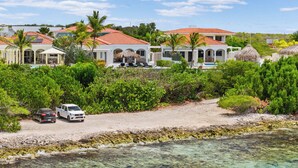 A beachfront property with multiple villas, a clear view of the ocean, and a sandy path leading to the beach. - Stunning Oceanfront Vacation Villa with Private Pool and Beach Access (Kralendijk)