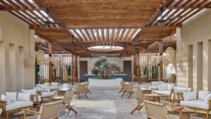 Un espace extérieur aménagé, abrité et doté de mobilier en bois et de lampes en osier suspendues.