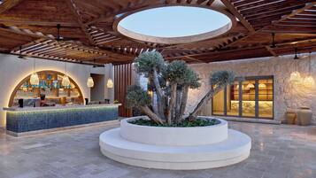 A bar area with a circular seating arrangement, a stone wall, and a wooden ceiling structure.