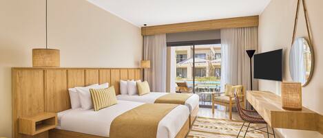 A hotel room with two beds, a TV, a desk, and a view of the outdoor pool area.