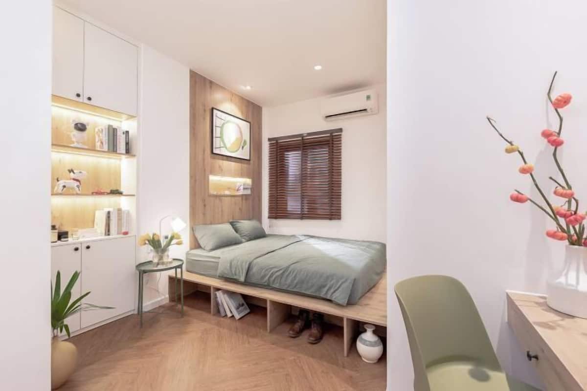 A compact bedroom with a bed, bedside table, and a small desk area.
