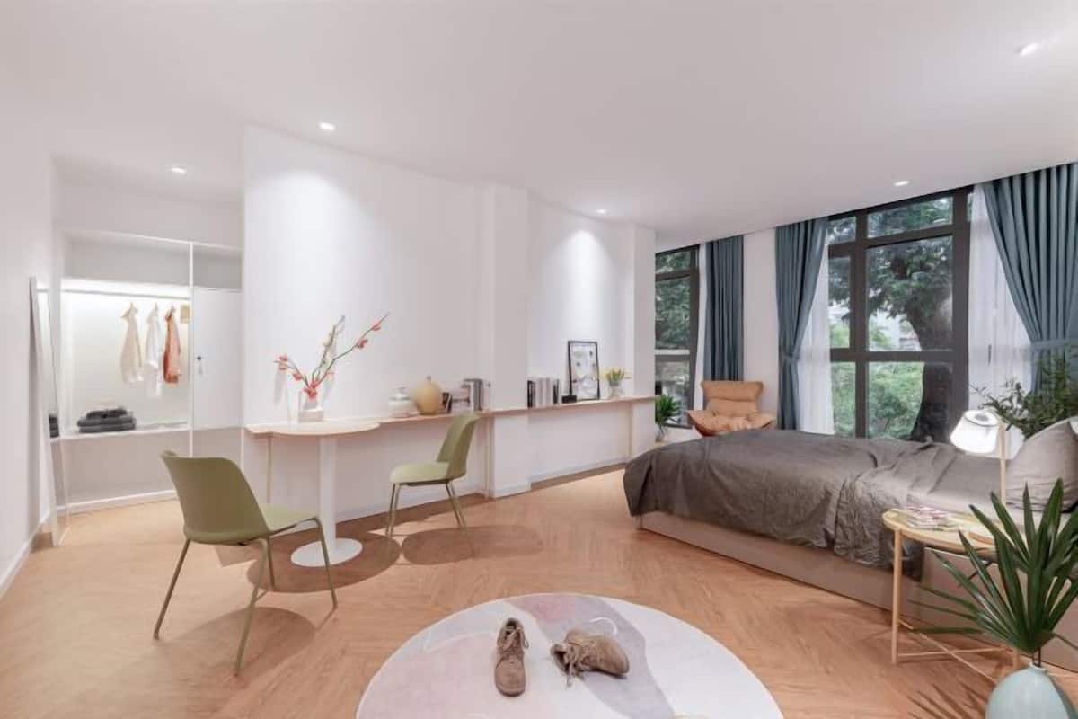 A modern bedroom with a bed, a desk, a chair, and a large window.
