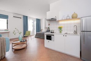 Egy modern konyha fehér szekrényekkel, beépített sütővel és rozsdamentes acél hűtőszekrénnyel.