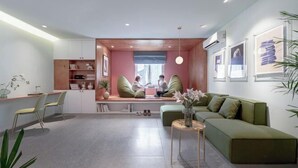 A modern living room with a green sofa, a wooden coffee table, and a seating area with a bench. - Express by M Village Dien Bien Phu Q3, a brand of Modern Village Lifestyle (Ho Chi Minh City)