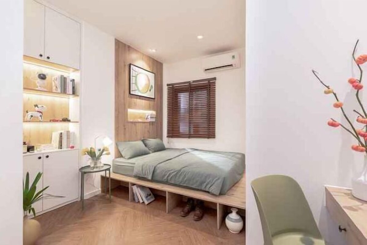 A compact bedroom with a bed, bedside table, and a small desk.