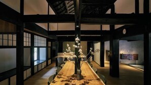 A traditional Japanese-style room with tatami flooring, a low table with a vase of flowers, and sliding doors. - RICKA KATSUURA (Katsuura)
