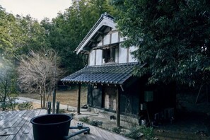 A traditional Japanese-style building with a tiled roof and wooden structure, surrounded by greenery. - RICKA KATSUURA (Katsuura)