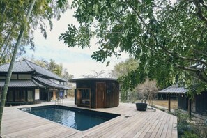A traditional Japanese-style building with a wooden deck, a hot tub, and a swimming pool. - RICKA KATSUURA (Katsuura)