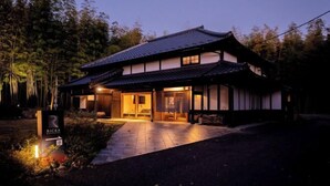 A traditional Japanese-style building with a dark roof, large sliding doors, and a well-lit entrance. - RICKA KATSUURA (Katsuura)