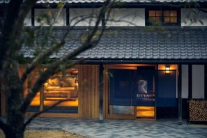 A traditional Japanese-style building with a tiled roof, a wooden facade, and a visible entrance with a sign. - RICKA KATSUURA (Katsuura)