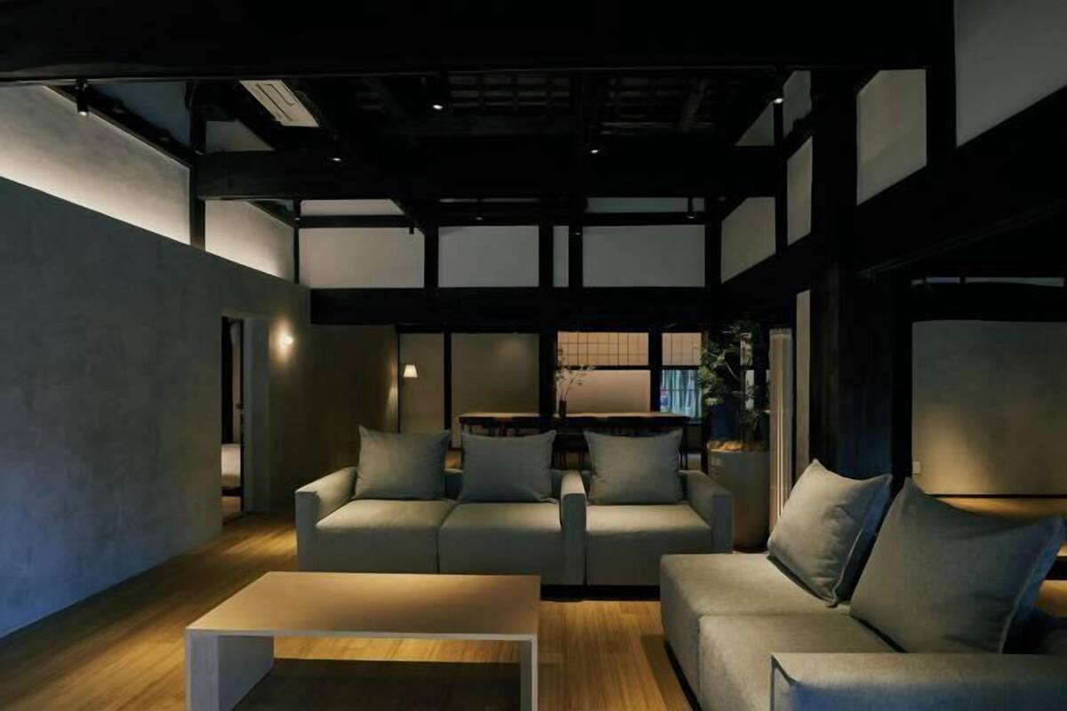 A modern living room with a sofa set, a coffee table, and a dining area in the background.