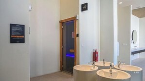 Un bagno moderno con tre lavabi, uno specchio e un ingresso verso la zona doccia.