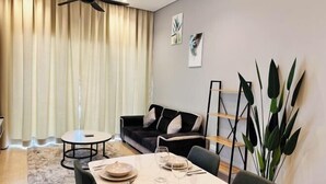 Zona pranzo con tavolo imbandito per quattro persone, un divano nero, una ventola a soffitto e una pianta grande.
