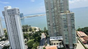 A high-rise building with multiple balconies, a waterfront view, and a parking area. - HappySty in George Town Amazing sea view (George Town)
