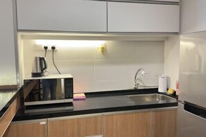 A modern kitchen with a black countertop, stainless steel appliances, and wooden cabinets. - HappySty in George Town Amazing sea view (George Town)