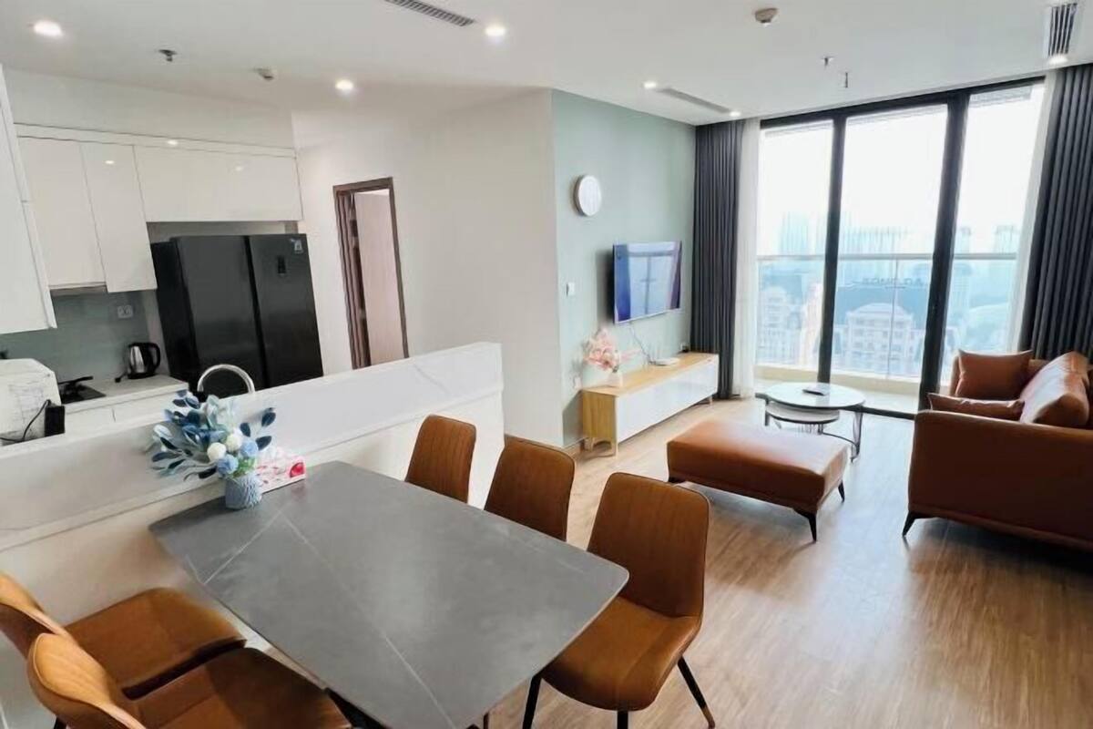 Une chambre d’hôtel moderne dotée d’un coin repas, d’une kitchenette et d’une grande fenêtre offrant une vue sur la ville.
