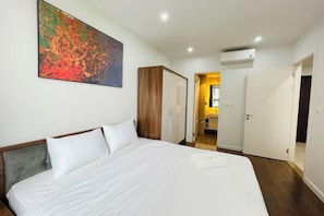 Une chambre d’hôtel avec un grand lit, une armoire, un tableau au mur et un appareil de climatisation.