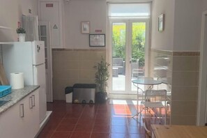 A compact kitchen with a refrigerator, sink, and countertop. There is a small dining area with a table and chairs. - HaoBo porto center (Porto)