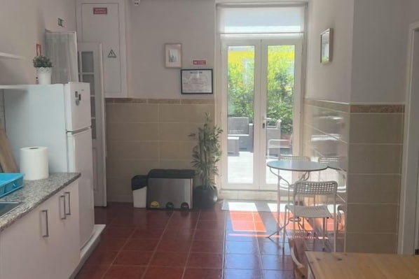 A kitchen with a refrigerator, stove, and sink. There is a dining table and chairs outside. - HaoBo porto center (Porto)