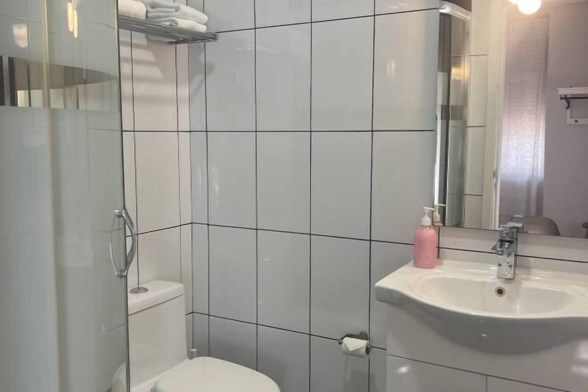 A bathroom with a white sink, a mirror, and a shower enclosure.