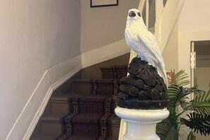 A white bird sculpture on a pedestal in a hallway with a staircase in the background. - HaoBo porto center (Porto)