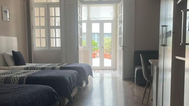 Une chambre avec deux lits, un bureau et une porte donnant sur un balcon.