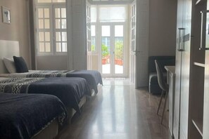 A room with two beds, a desk, and a door leading to a balcony. - HaoBo porto center (Porto)