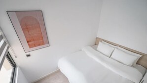 A bedroom with a bed, a window, and a wall-mounted artwork. - Luxury Apartment in Vinhomes D'Capitale by David Home (Hanoi)